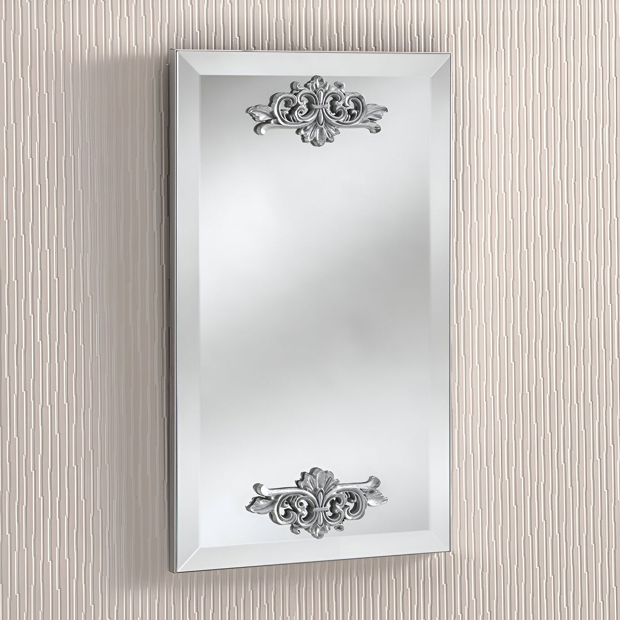 The Crest Rectangle Wall Mirror - White, featuring its ornate silver decorative elements and beveled edge, is ideal for vintage-inspired interiors. Mounted on a textured cream-colored wall, this decorative mirror brings an elegant touch to any space.