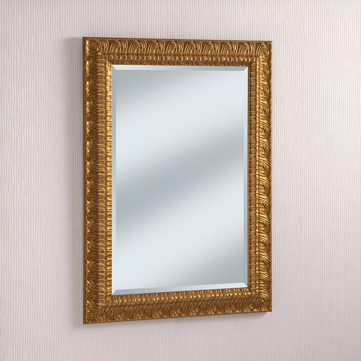 A Crown Rectangle Wall Mirror in dark gold, adorned with an ornate frame featuring intricate patterns, is elegantly mounted on a textured, neutral-colored wall.