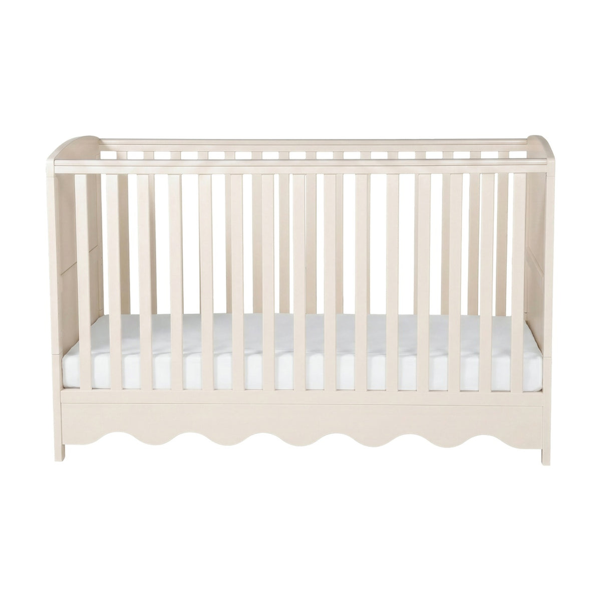 Dancer cot bed in Cashmere finish with slatted sides, scalloped front panel and white mattress base, shown on a plain white background.