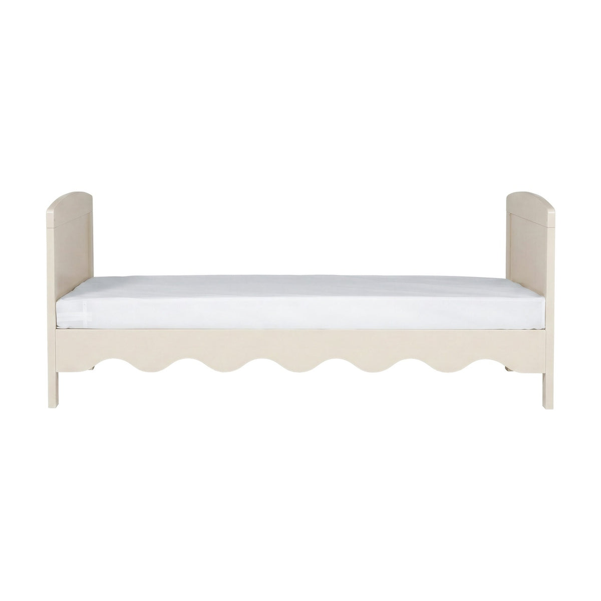 Dancer nursery cot bed in Cashmere finish with scalloped front panel, curved headboard and footboard, MDF frame, shown with mattress on a plain white background.