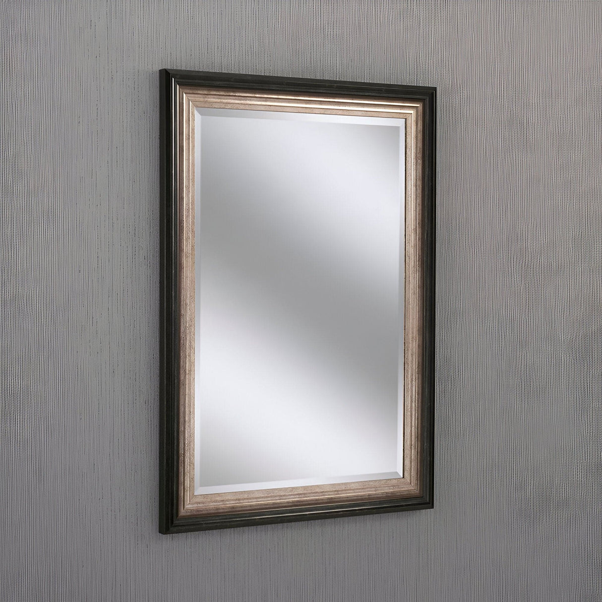 The Deco Rectangle Wall Mirror - Bronze/Silver features a dark beveled frame with a metallic silver finish, enhancing modern transitional interiors by reflecting simple bronze and silver tones on a textured light gray wall.