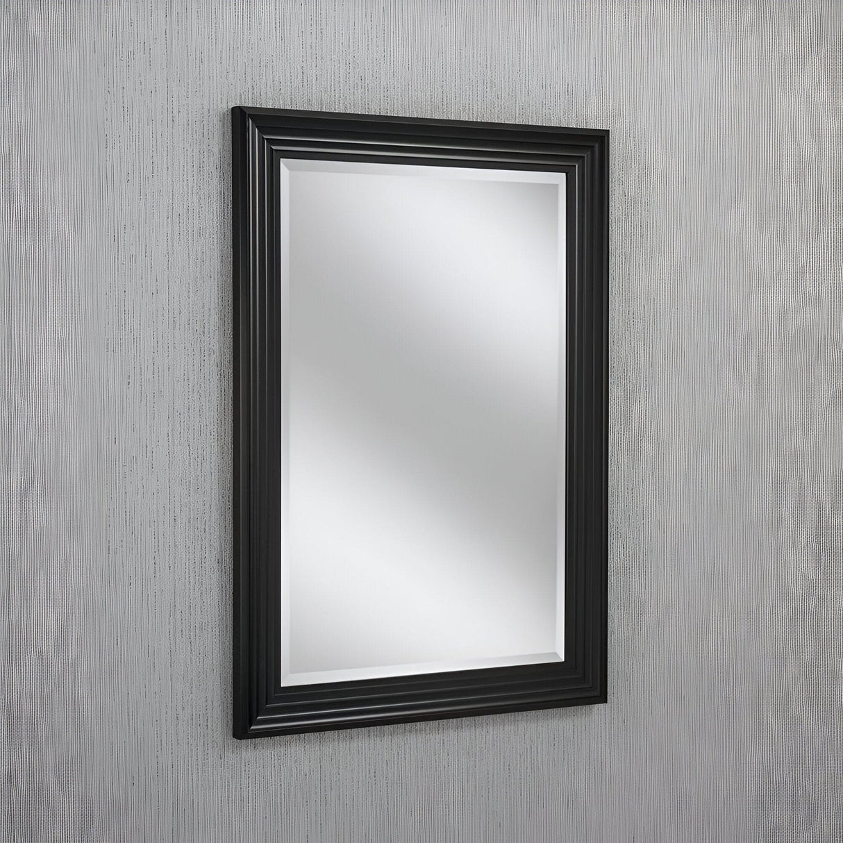The Deco Rectangle Wall Mirror - Black is centered on a textured grey wall, reflecting light softly to enhance the simple and modern design.