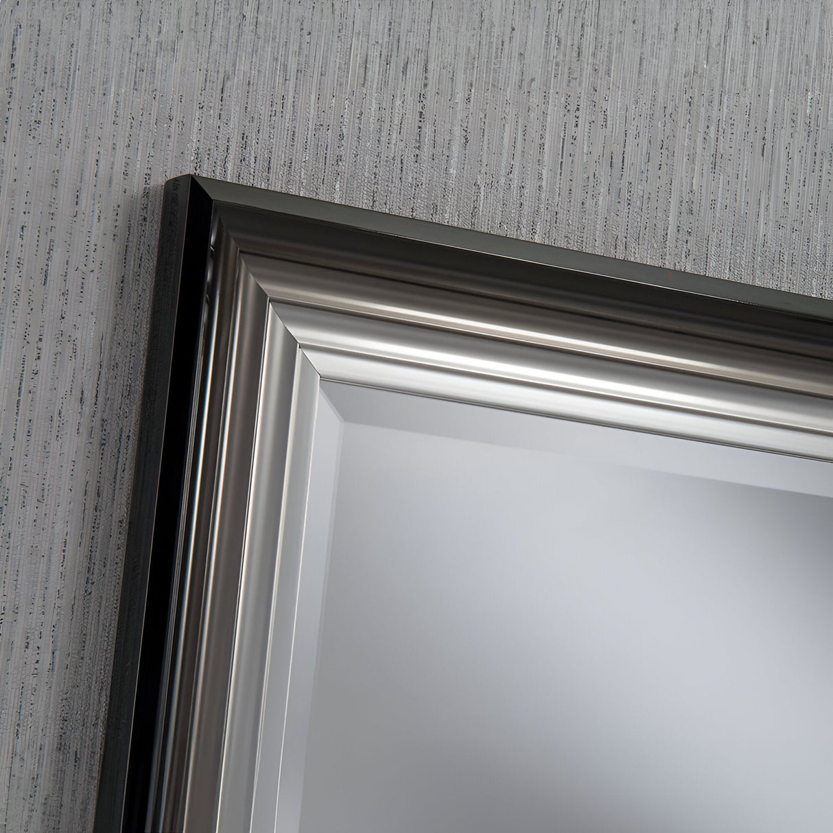 Close-up of the Deco Rectangle Wall Mirror - Black/Silver with a sleek, metallic frame mounted on a textured gray wall. The modern edge of the black and silver frame features a polished finish, reflecting a soft, neutral hue.