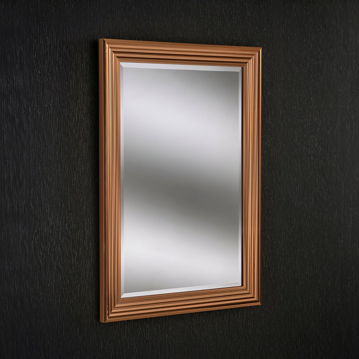 The Deco Rectangle Wall Mirror - Copper, featuring a golden brown frame with a layered design that adds depth and elegance, is mounted on a dark textured wall as part of this modern home decor.