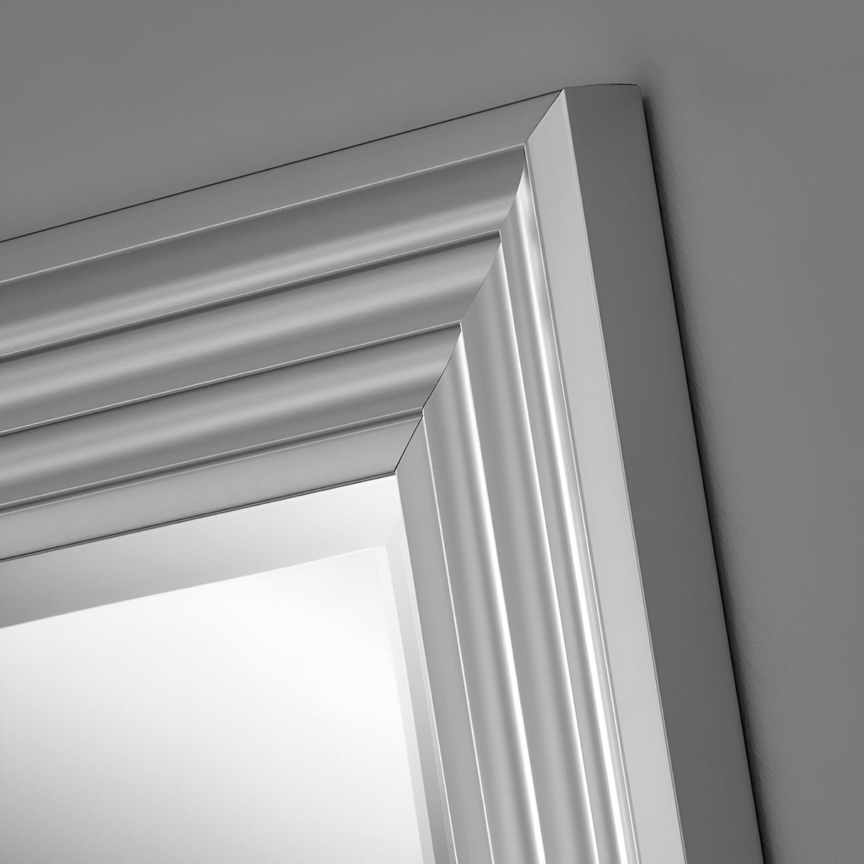 Close-up of the Deco Rectangle Wall Mirror in Matt Silver, showcasing its elegant angled frame with layered and beveled detailing. Set against a gray background, this sophisticated design offers a truly modern look.