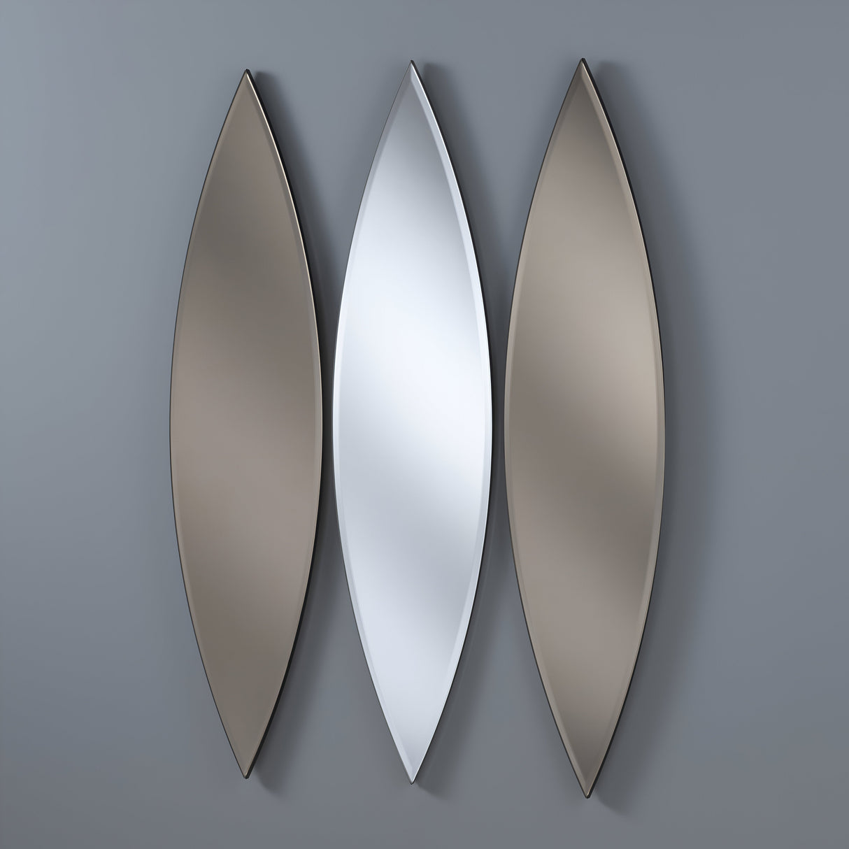 The Velouria Oval Wall Mirror set features three elongated, leaf-shaped mirrors (130x30cm each) on a gray wall. A silver central mirror is flanked by two with a warm bronze tint, creating an elegant and symmetrical modern design in your home decor.