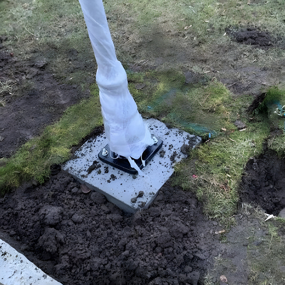 Medium Foundation Frame 150mm square in galvanised steel, set in a concrete base with bolts securing a wrapped post, installed outdoors in freshly dug soil and grass.