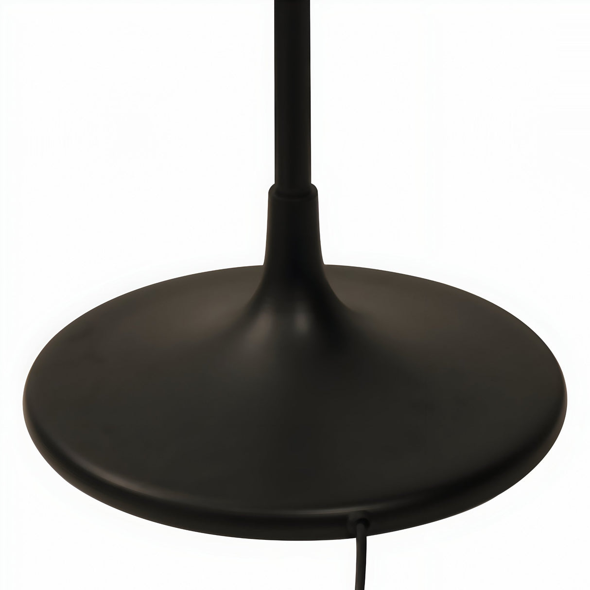 Close-up of the Niori Funk Industrial Floor Lamp's matt black weighted disc base and slim stem, with power cord visible on a plain white background.