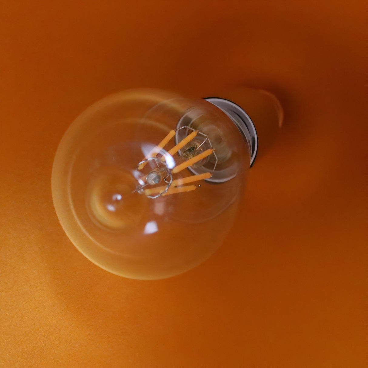 The Funk Stout Small Pendant Light - White is showcased against a vibrant orange background, photographed from above—an ideal accent for minimalist or modern interiors.