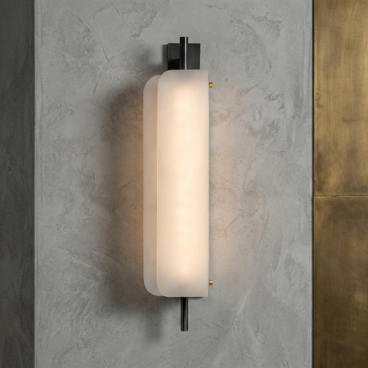 The Velisse LED Vertical Core Alabaster Wall Light features a modern, sculptural design with a frosted oval alabaster shade, black vertical fixture, and brass accent on the right side—perfect for mounting on concrete walls.