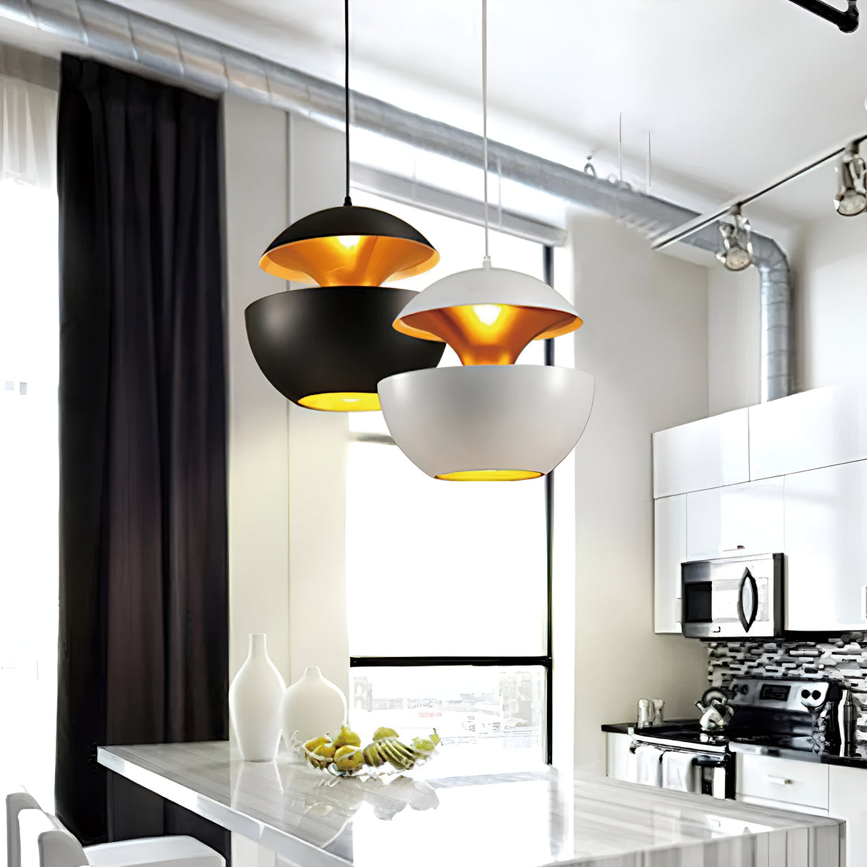 The modern kitchen features an Ex-Display Core Pendant in Copper & White (35cm), with two dome-shaped pendants over a sleek countertop, stainless steel microwave, white cabinets, black backsplash, and a bowl of green apples.