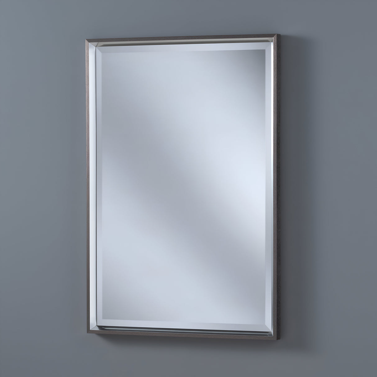 The Ambriss Rectangle Wall Mirror - Grey is mounted on a gray wall, softly reflecting light with its sleek metallic frame. Its minimalist design brings contemporary elegance, enhancing any modern space with sophistication.