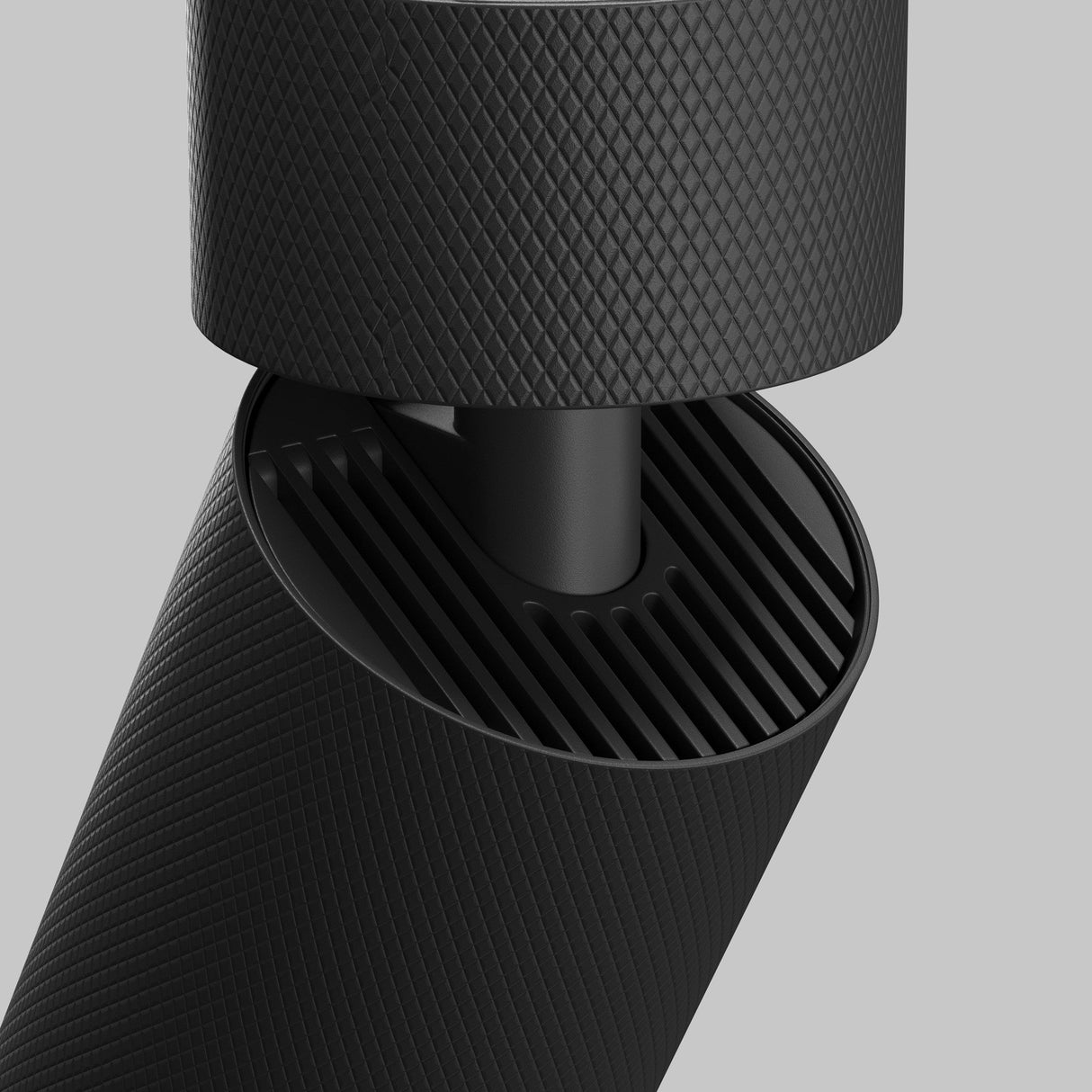A close-up of a sleek, modern black textured gadget with interlocking parts against a gray background, highlighting its fine ridges and cylindrical design. This minimalist look echoes the Artisan Single Spotlight - Black for customizable lighting solutions.