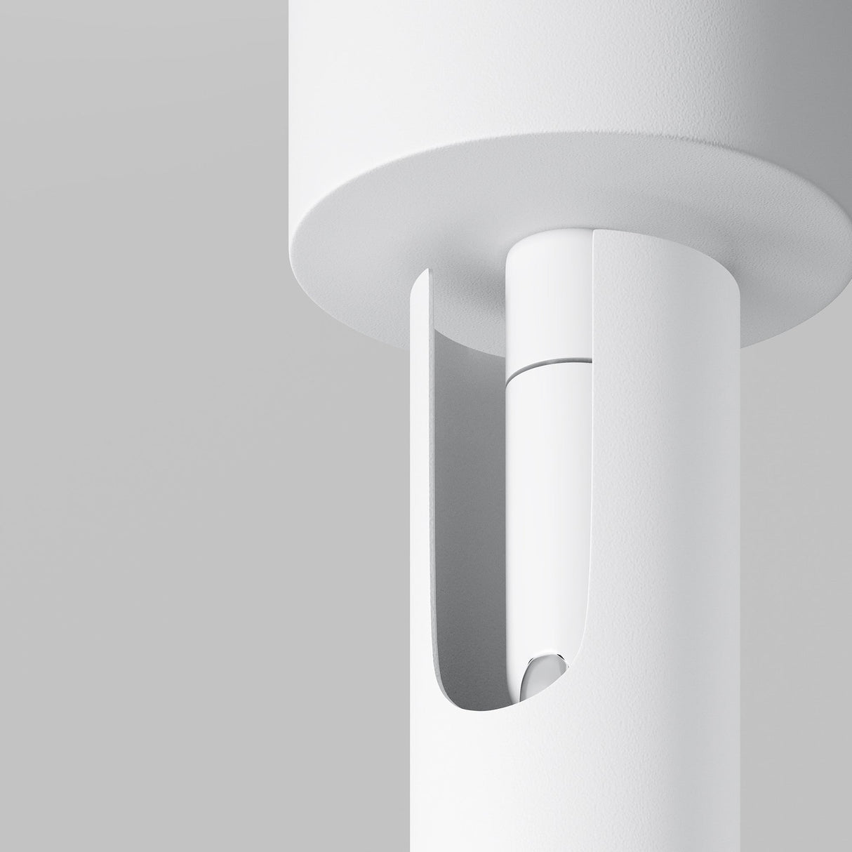 Close-up of the Focus T LED Long Single Spotlight 6W 3000K - White, showcasing its minimalist design featuring a cylindrical base with a cut-out section. The plain light gray background highlights the sleek Scandinavian style of the lamp.