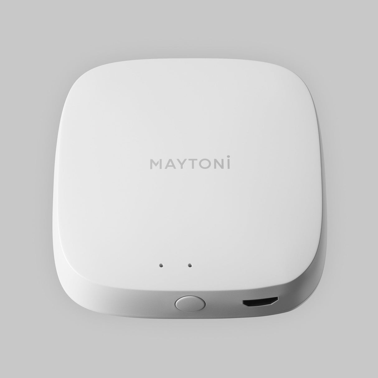The white, square-shaped Smart Home Control Wi-Fi Module by MAYTONi features rounded edges, two small holes, a circular button on the front, and a Wi-Fi module port on the right. Its ideal for smart home integration and is set against a light gray background.