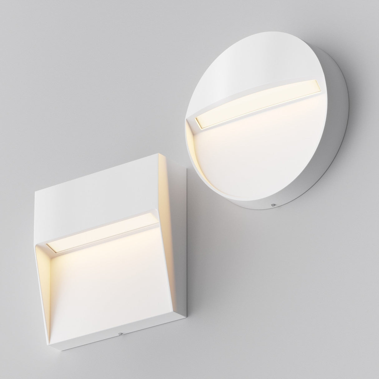 Two Mane Outdoor LED Round Wall Lights in white are set against a light gray background. One lamp is round, and the other is square. Both feature minimalist, energy-efficient LED design with recessed lighting that emits a soft glow, enhancing their modern appeal.