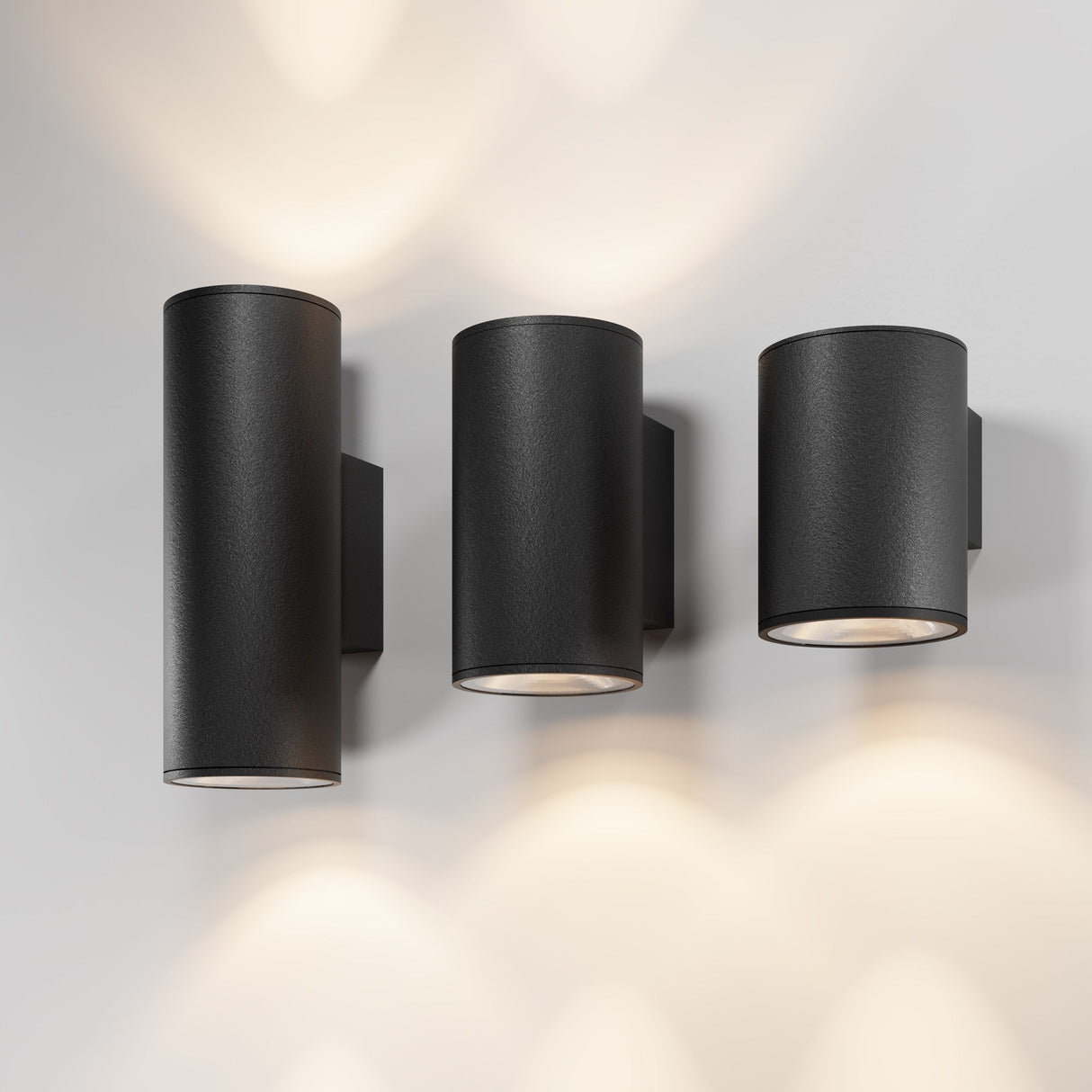 Three Shim Outdoor Wall Lights 5W 3000K, with a sleek graphite finish and IP65 rating, are mounted in a row on a light-colored wall. They cast bright upward and downward glows for soft illumination.