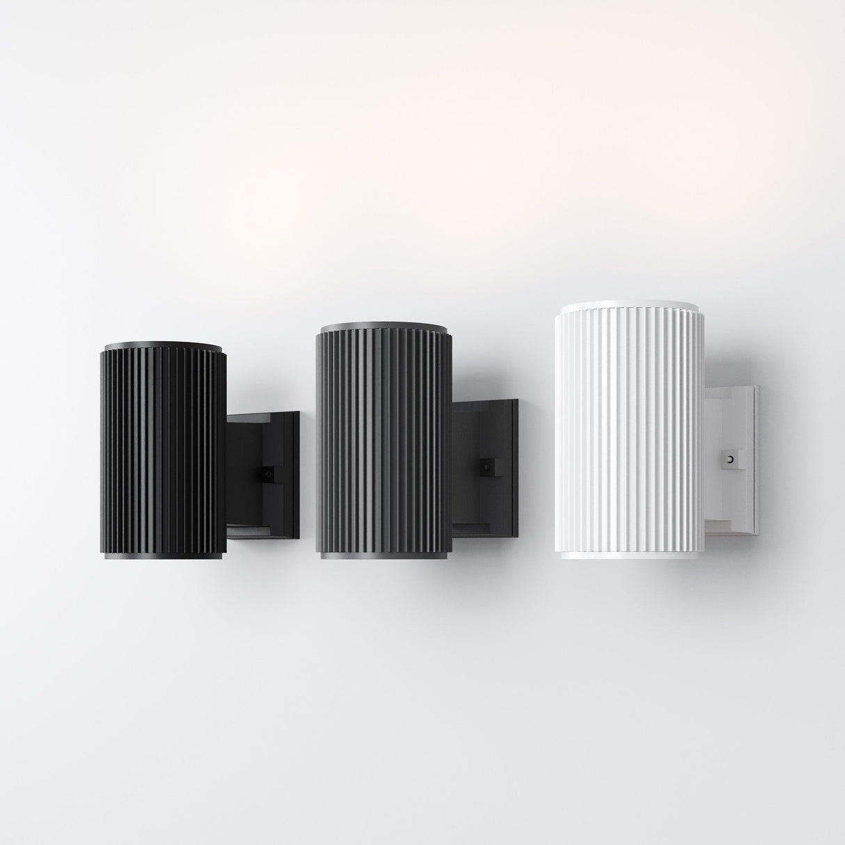 Three Rando Outdoor Wall Lights with a ribbed texture are mounted on a plain white wall. Featuring an IP54 rating, these corrosion-resistant sconces include two in black and one in white, arranged from left to right.