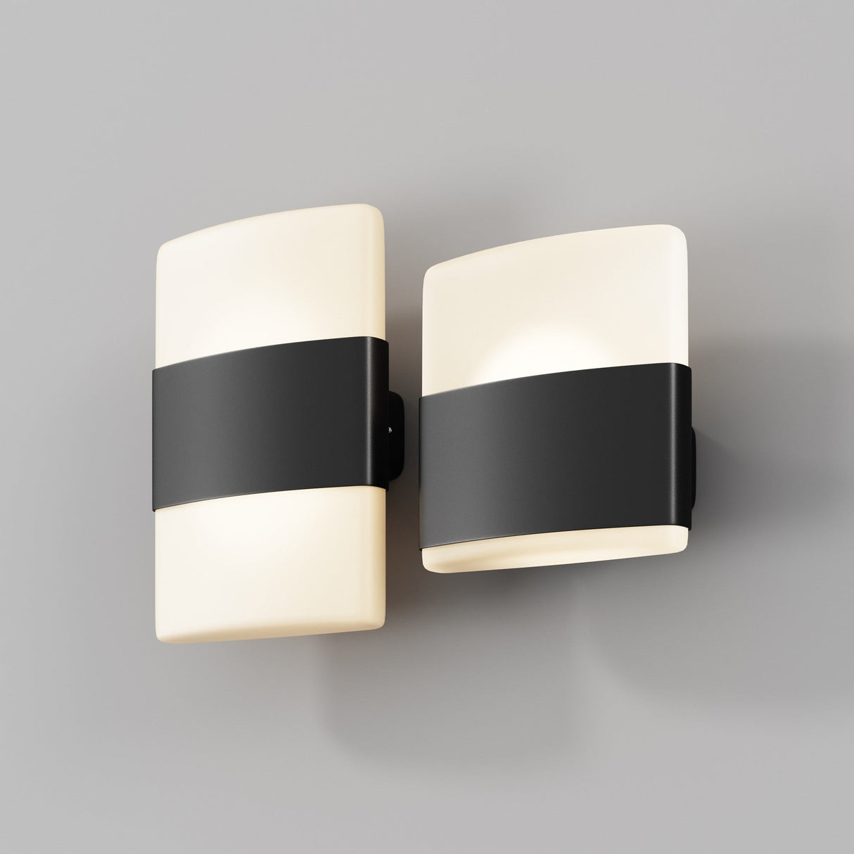 Two modern Rom Outdoor LED Up & Down Wall Lights in graphite, featuring white bodies with black bands, are mounted on a light gray wall. These IP54-rated fixtures cast a soft glow when illuminated.