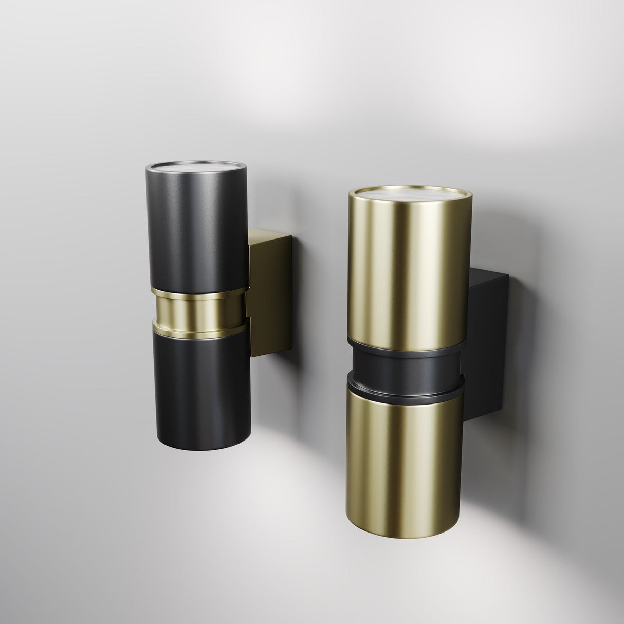 Two cylindrical wall lights, ideal for outdoor use, are mounted side by side on a light gray wall. One is metallic gold with a black base, the other is matte black (Bowery Outdoor 2 Light Wall Light - Black, O582WL-02B). With brass accents and dual-end lighting, they have an IP54 durability rating.