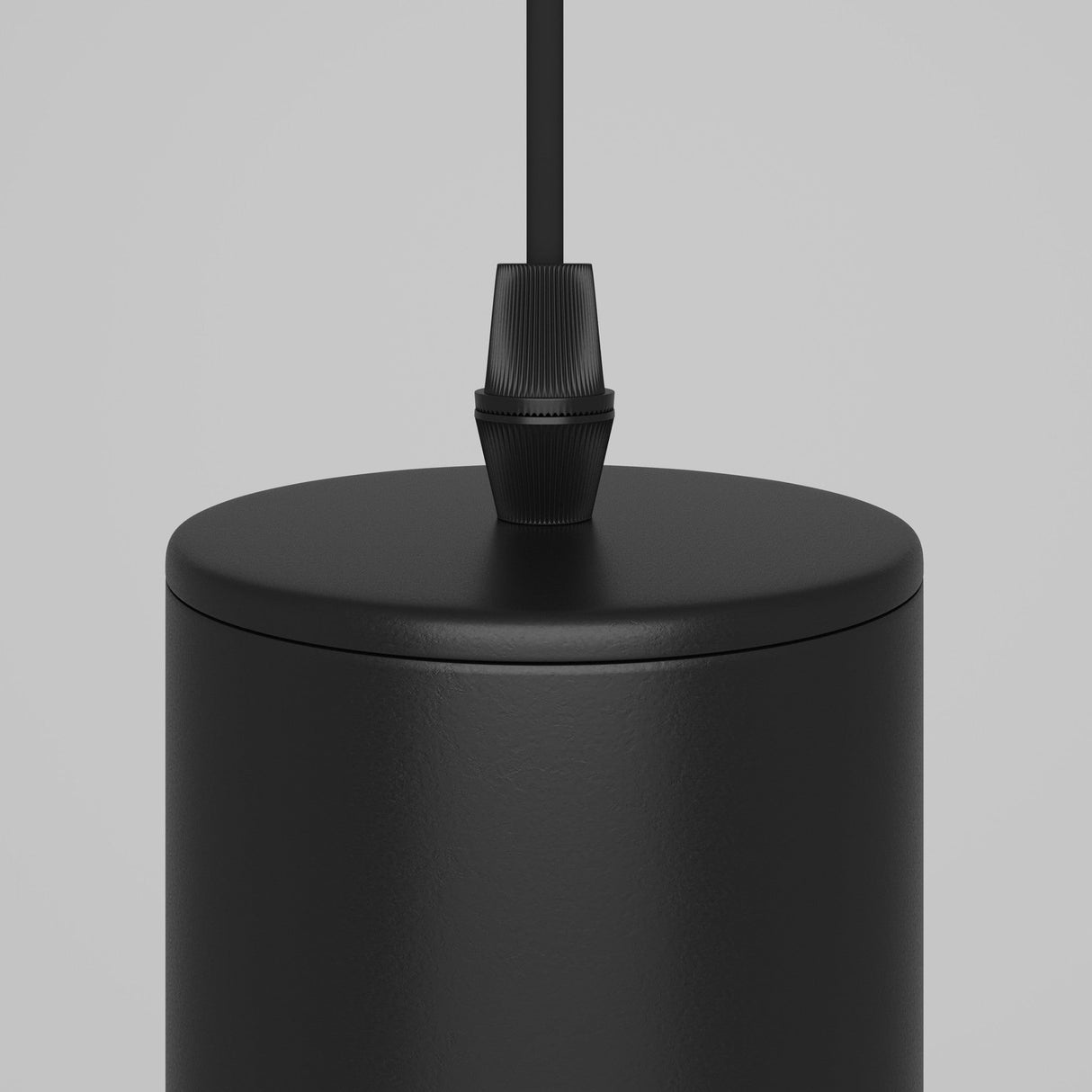 Close-up of the Focus Single Pendant Light - Black, featuring a modern industrial design with a cylindrical black metal finish and an attached black cable, set against a plain gray background.