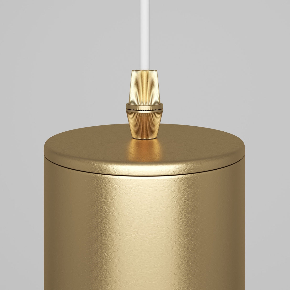 A close-up of the Focus Single Pendant Light in matte gold against a light gray background, featuring a textured finish. A white cord elegantly extends from the top, connecting to a small gold fitting.