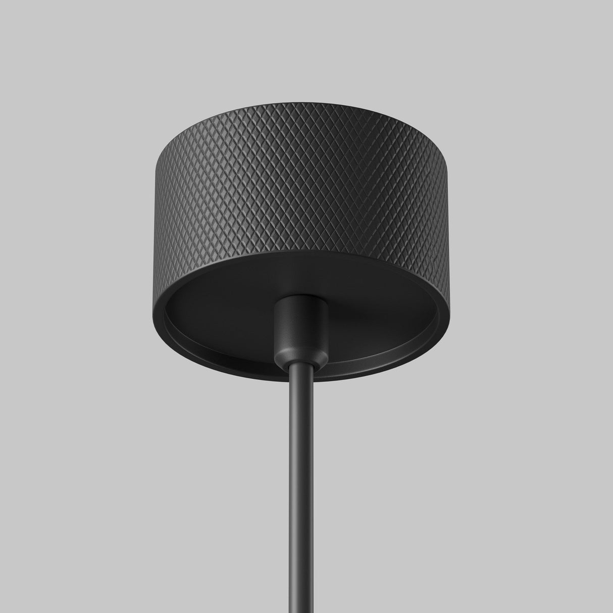 Close-up of the Artisan 1 Light Long Round Pendant in black against a gray backdrop, featuring a textured geometric pattern with an elegant finish and a central rod extending downward.