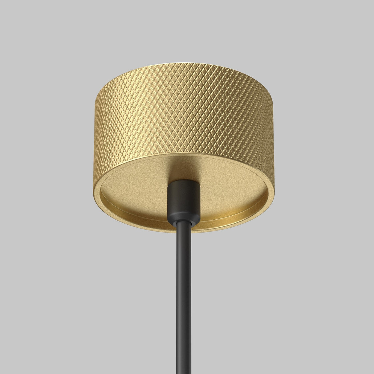 Close-up of the Artisan 1 Light Long Round Pendant in Matte Gold, featuring a textured surface on a modern, minimalist design. It hangs from a black pole against a gray backdrop.