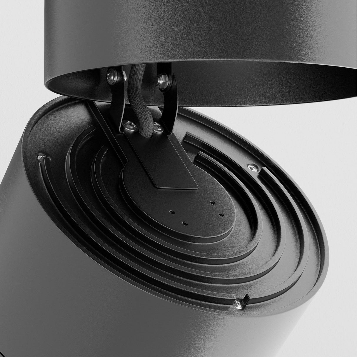 This close-up highlights the Yin LED Single Phase Unity Track Spotlight, a modern black metal ceiling light with a cylindrical design, featuring adjustable components and a swivel mechanism. Visible screws and wiring emphasize its industrial style against a white background.