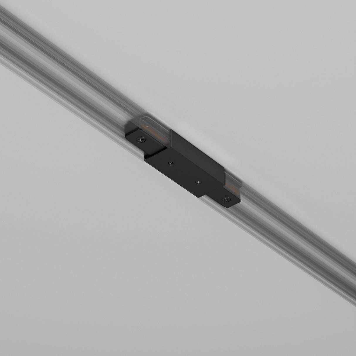 A detailed view of the Unity Single Phase Track Middle Feed Connector in black, mounted on a sleek, glossy surface. The design is minimal and modern.