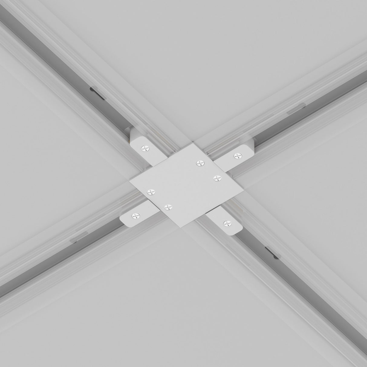 Close-up of a Unity Tracks Recessed X-Shaped Connector in white, with visible screws, seamlessly intersecting four ceiling grid tracks for track lighting against a smooth, light grey background.