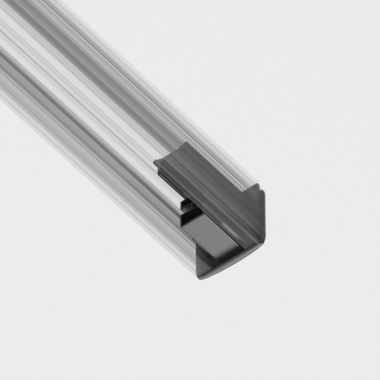 A close-up of a 3-Phase Surface-Mounted Track Trinity End Cap in black, with a triangular tab, highlights the contrast between its textured appearance and the metallic rails smooth surface, akin to elements found in track lighting systems, set against a plain white background.