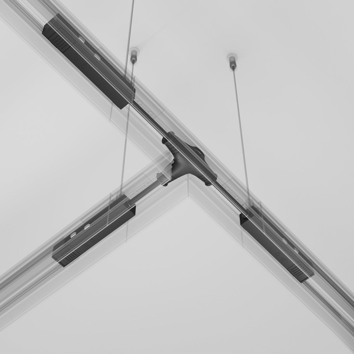 A close-up of a modern ceiling rail showcases intersecting tracks and suspended cables with the sleek Exility Tracks Magnetic T-Connector Power Feed in black, seamlessly integrating into the white ceiling.