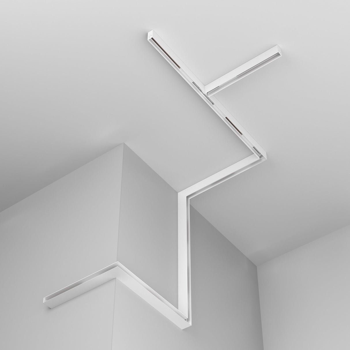 The Exility Magnetic Surface-Mounted Track 2 Pack End Cap in White creates a minimalist look with its modern, geometric zigzag design elegantly spanning the ceiling and wall intersection, adding sleek, angular lines to your contemporary space.