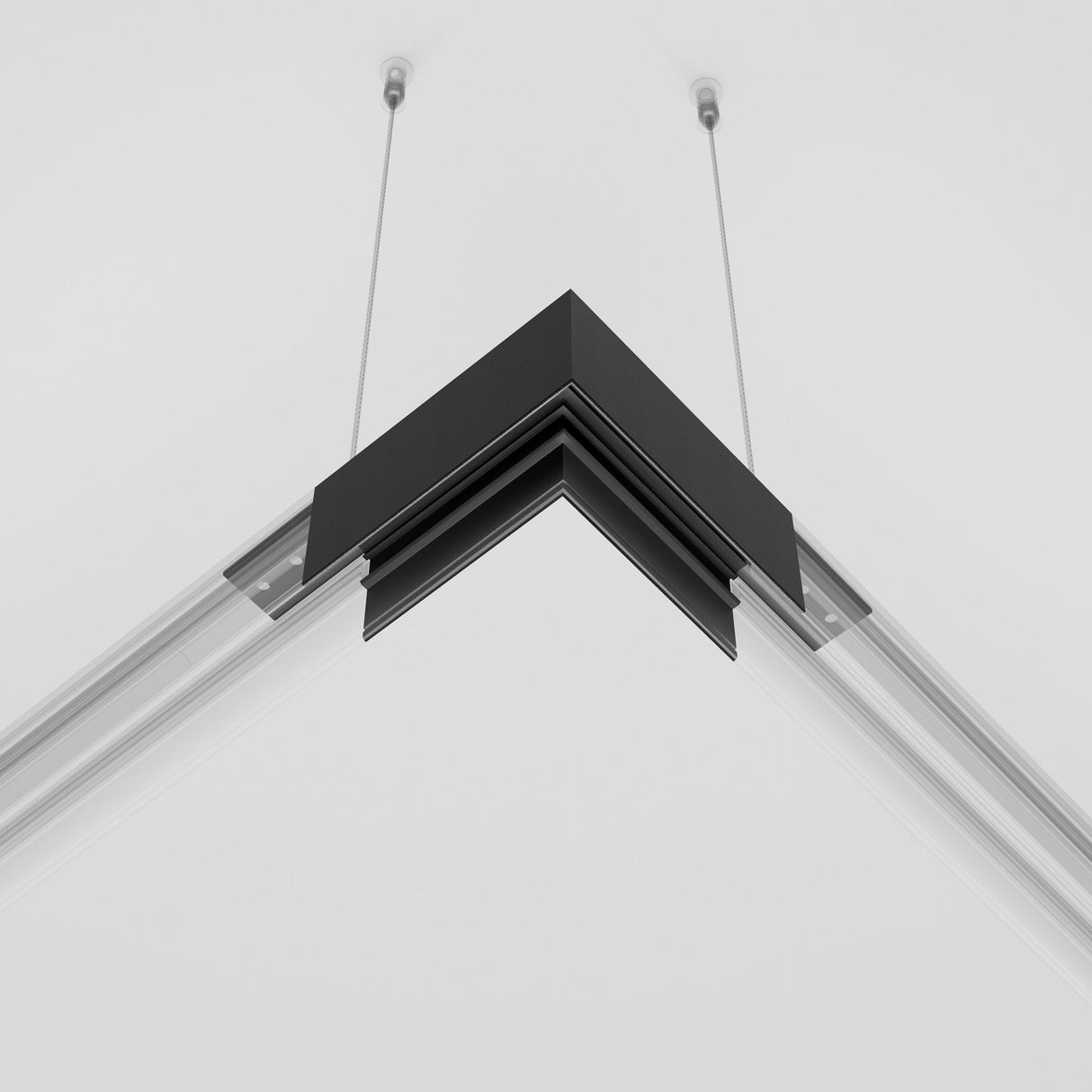 Close-up of the Exility Magnetic Surface-Mounted Track Corner Connector in black, with angular transparent panels. Secured by two thin cables, it adds a sleek touch to the plain white ceiling.