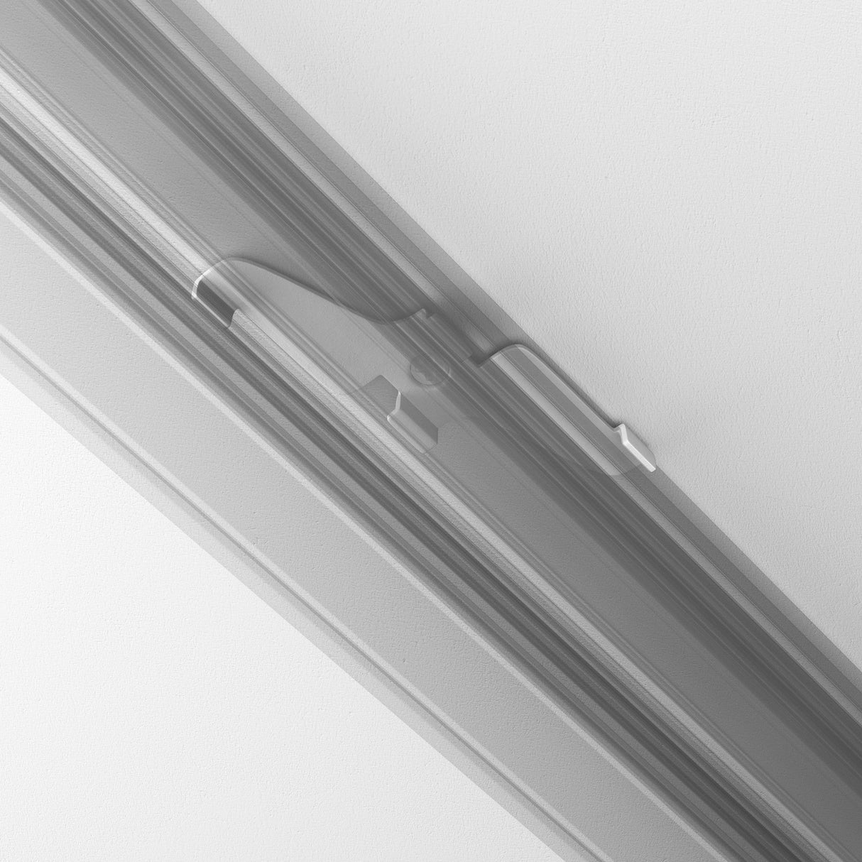 A close-up image showcases the Exility Magnetic Track Clamp - White, highlighting its sliding latch mechanism within a groove. The latch handle is centrally positioned with a recessed section for easy use, set against a minimalist monochromatic backdrop.