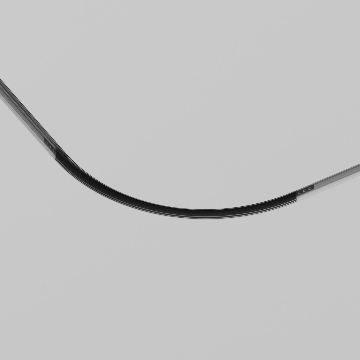 Close-up image of the Exility Tracks Radius Connector R300, a sleek black object with metallic accents against a gray backdrop. The minimalist design features reflective surfaces and exudes modernity with its bold, abstract aesthetic for plasterboard integration.