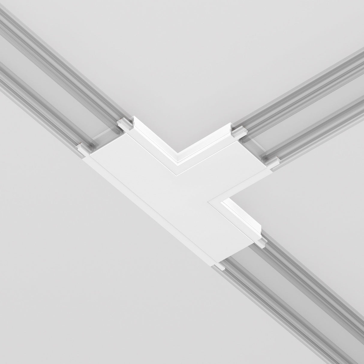 A close-up of the Radity Magnetic Track T-Shaped Power Connector - White against a smooth, light-colored ceiling highlights its recessed lines, clean lines, and geometric shapes, enhancing the modern aesthetic of minimalist interiors.