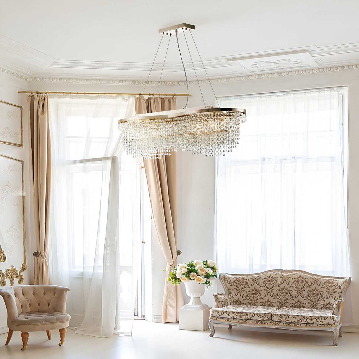 A luxurious living room showcases the Toils 7 Light Crystal Suspension in gold, cream curtains, vintage-style sofa with ornate patterns, a small upholstered chair to the left, and a flower bouquet on a side table. Natural light beautifully illuminates the elegant space.