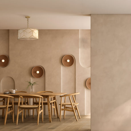 A minimalist dining room showcases a wooden table with six chairs. Beige walls hold round, sculptural accents, and the elegant Messina Chandelier - Gold adorns the ceiling. The table is beautifully set with a tea set and a single flower.