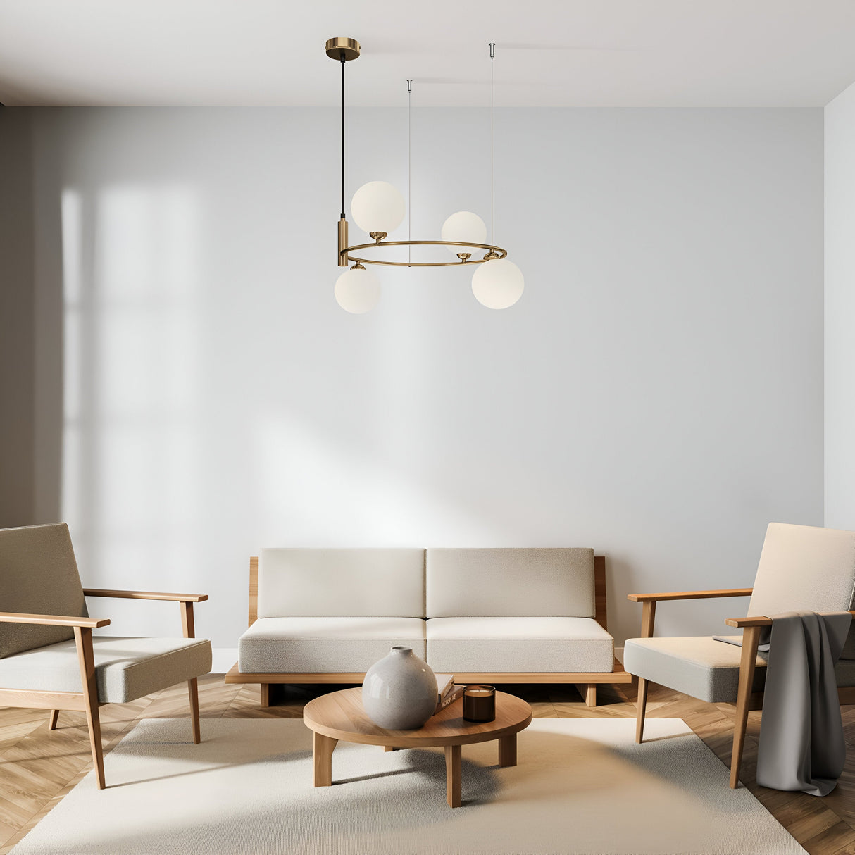 A minimalist living room includes a white sofa, two beige armchairs, and a round wooden coffee table with a grey vase. The Ring 4 Light Circular Suspension in gold with white glass boldly hangs from the ceiling, enhancing the rooms light walls and neutral color palette.