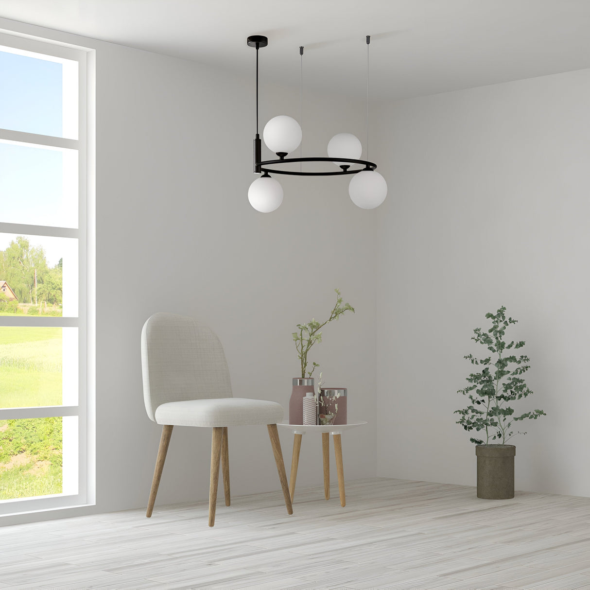 In a minimalist room with light wood flooring, a round white side table holds vases and a plant. Nearby, a white chair with wooden legs complements the decor. The focal point is the Ring 4 Light Circular Suspension in black with white glass, while large windows showcase the green landscape outside.
