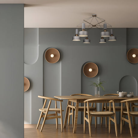 A modern dining room features a round wooden table with matching chairs, gray walls with circular recessed lights, and the Void 6 Light Chandelier - Grey overhead. A small plant on the table completes the sleek modern design.