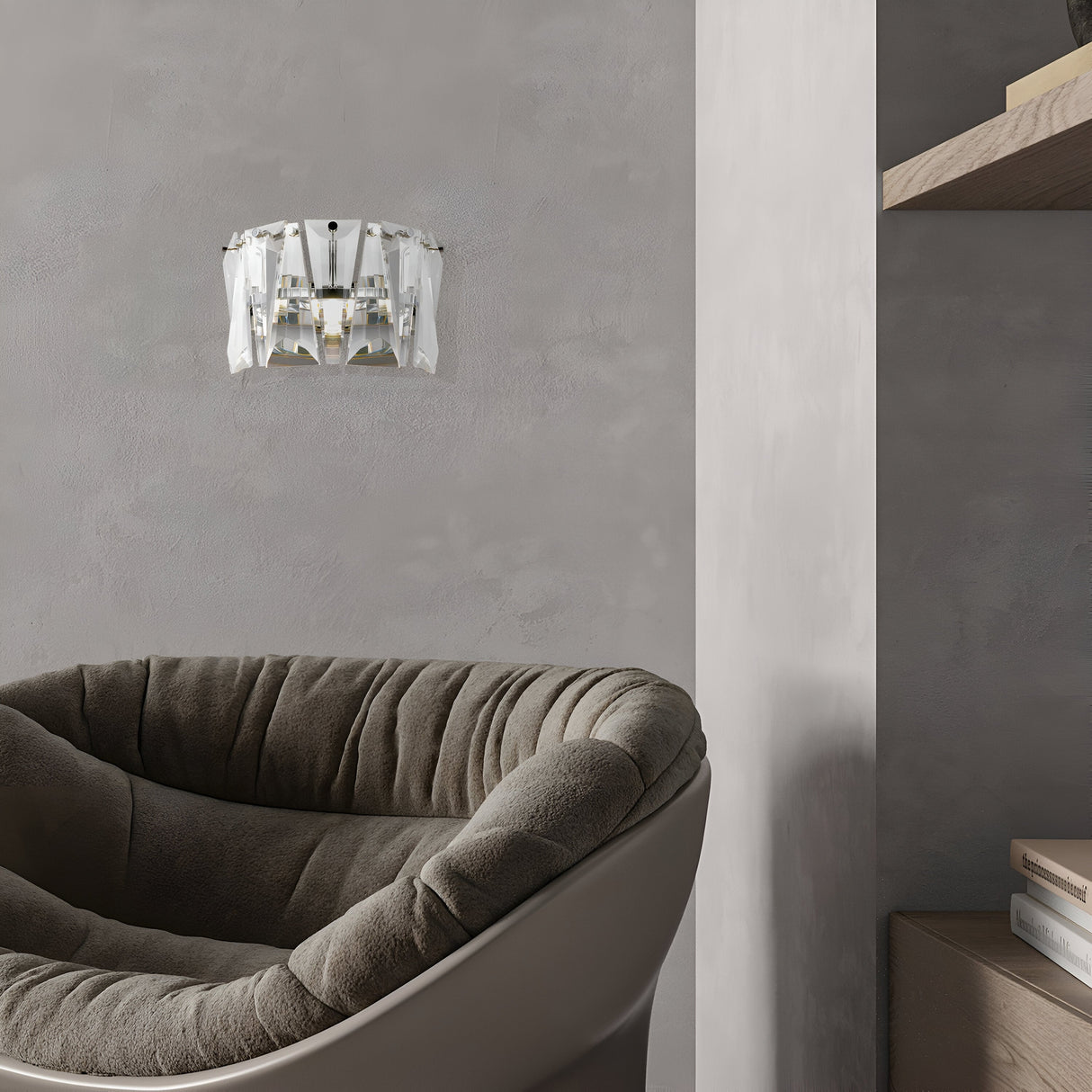A modern interior with a gray textured wall features a plush green armchair and a wooden shelf. Above the chair, the Puntes Wall Light in chrome and crystal boasts a geometric design, adding elegance to the minimalist setting.