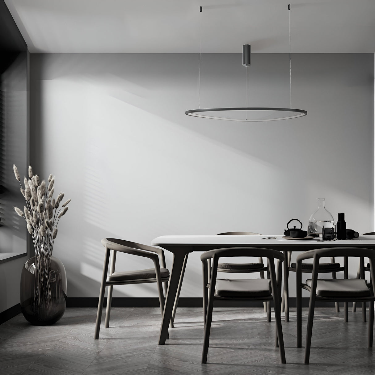 Minimalist dining area with a sleek table and four modern chairs. A vase of decorative branches in the corner, while the Glint LED Circular Suspension Light 80cm - Black, with adjustable height, casts soft shadows on light grey walls and herringbone-patterned floors.