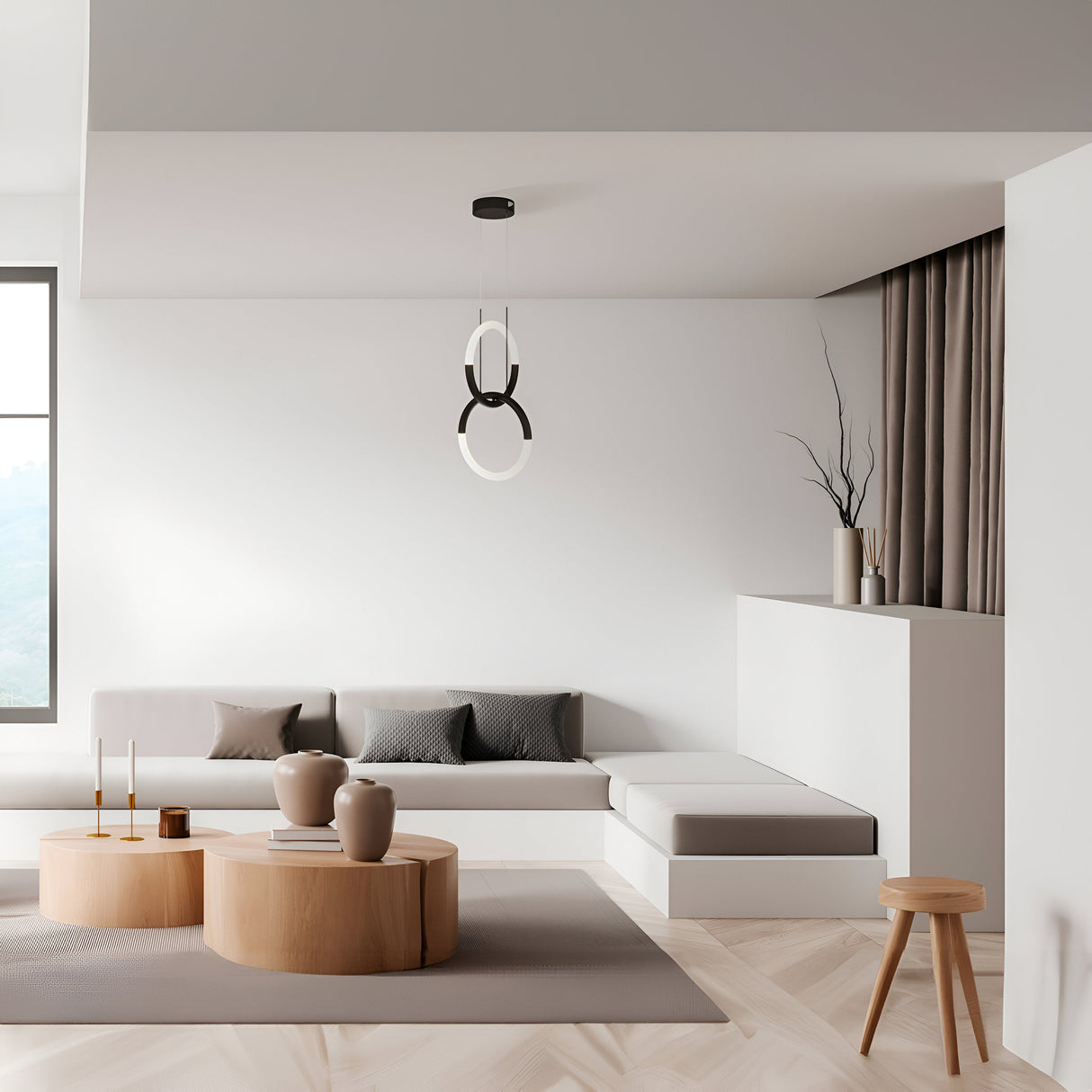 A modern minimalist living room showcases a gray sectional sofa, wooden coffee tables with vases, and a small stool. The Node LED 2 Rings Pendant Light - Black hangs as a geometric chandelier, while light gray walls, sheer curtains, and a large window create an airy atmosphere.