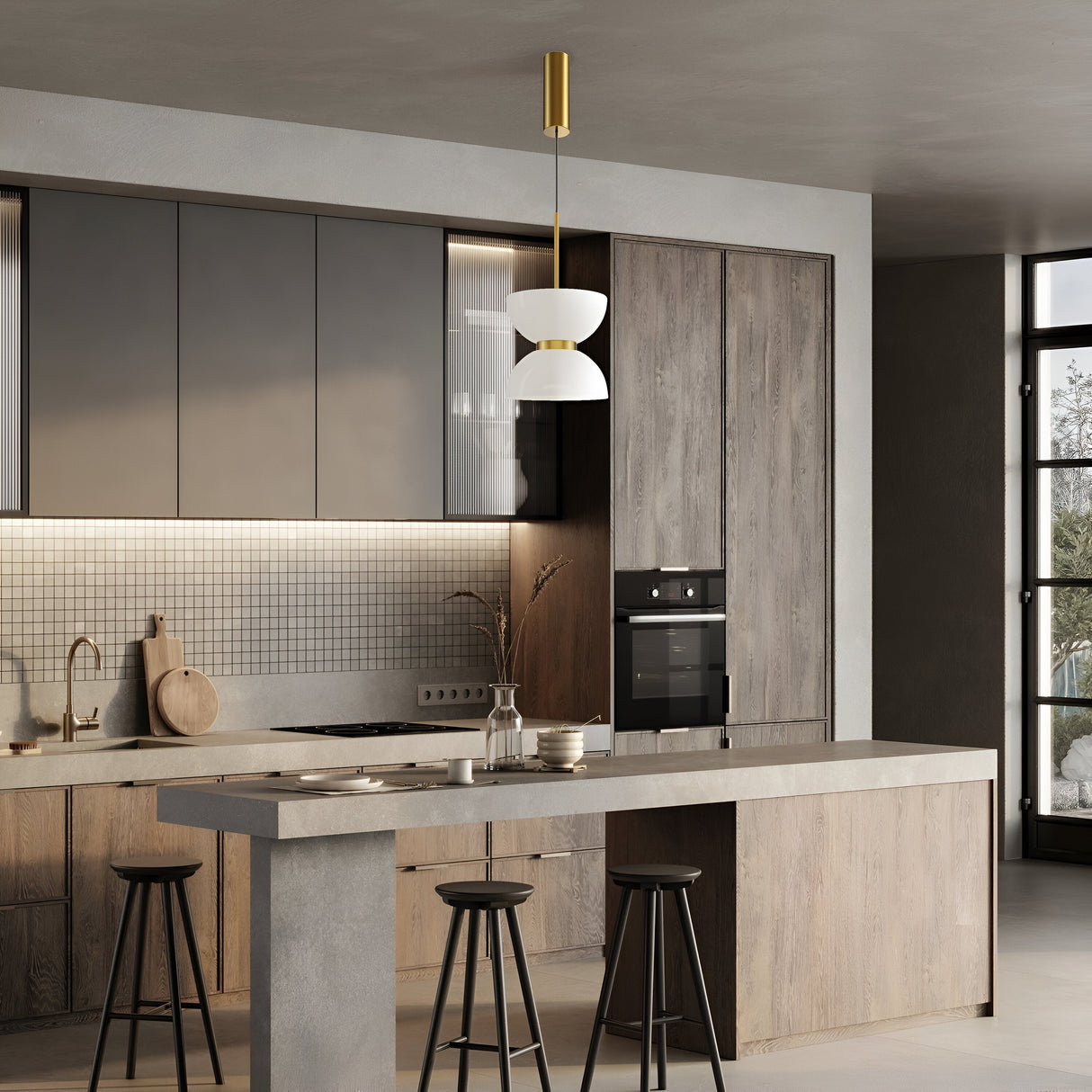 Modern kitchen with gray and wood cabinets, featuring a central island with three black stools and a sleek Kyoto LED Pendant Light, Gold with Glossy White Glass. The gray tiled backsplash, paired with a window on the right, enhances the minimalist décor and energy-efficient lighting for an open design.