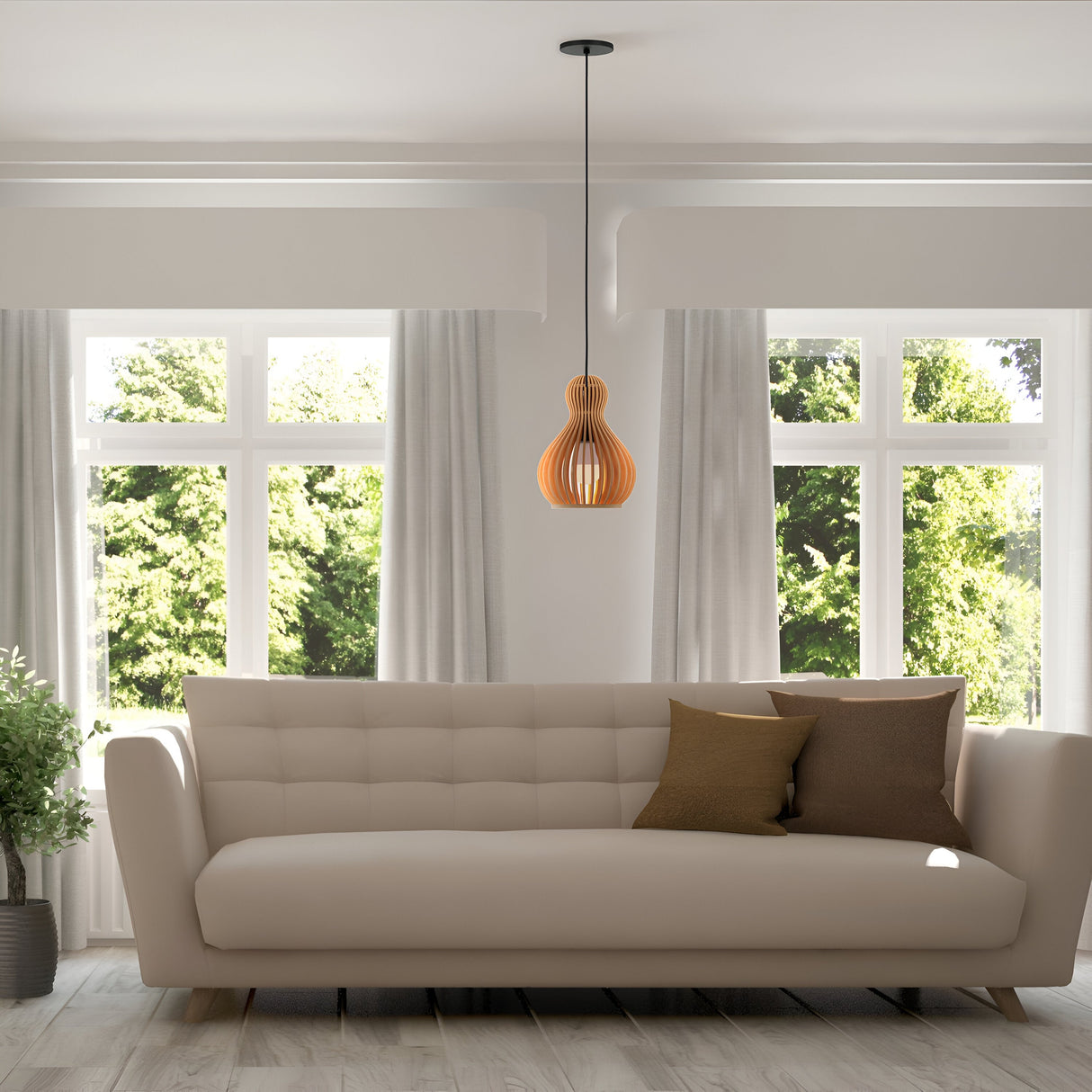 In a modern living room, a cream-colored sofa is adorned with brown throw pillows under the Roots Pendant Lamp featuring a black base and beige wooden dome shade that casts a warm glow. Large windows with sheer curtains reveal lush green trees, and a potted plant enhances the natural ambiance.