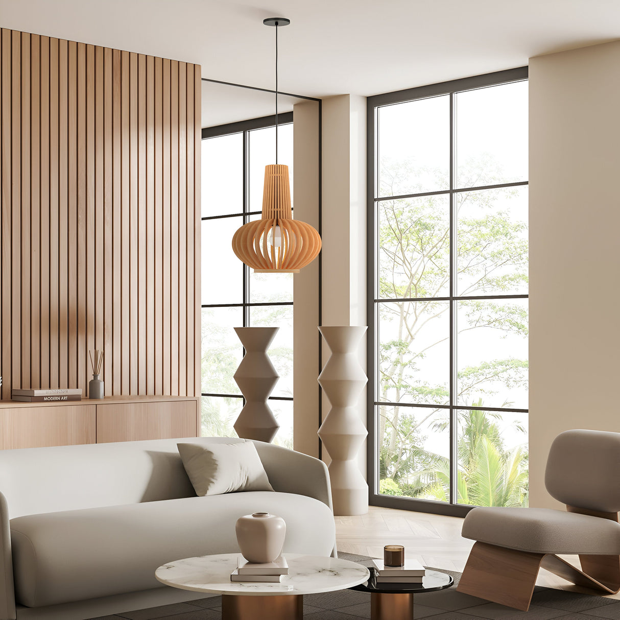 A modern living room with large windows includes a light gray sofa, a round marble coffee table with a vase, and a sculptural chair beneath the Roots Pendant Light (35cm) in black with a beige wooden oval shade, complementing the vertical wooden paneling and abstract floor sculptures.