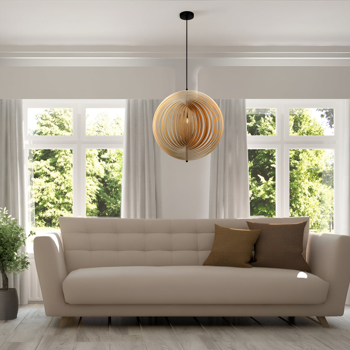 In a modern living room filled with contemporary elegance, a cream sofa is decorated with two brown cushions. Above it hangs the 60cm Roots Pendant Light, featuring black and natural wood sphere rings. Large windows reveal green trees, allowing bright natural light to flood in.